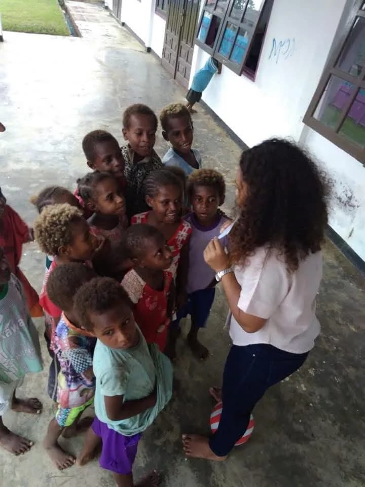 A volunteer engaging with children outdoors in a Papuan community